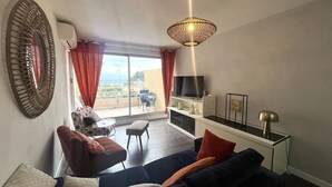 Ett vardagsrum med en soffa, en tv och en balkong med utsikt.