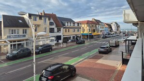 En gatubild med byggnader, bilar och en grön cykelbana.