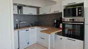 Ett kompakt kök med diskmaskin, kaffebryggare och mikrovågsugn.