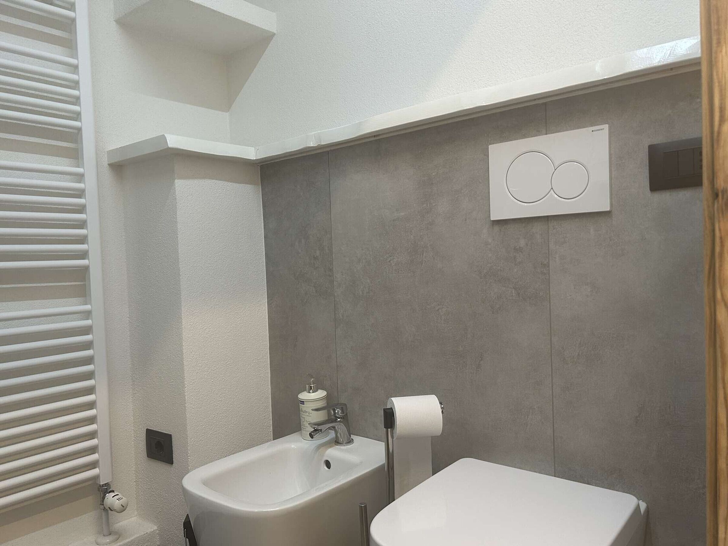 Une salle de bain moderne avec un lavabo blanc, des toilettes et un porte-serviettes.