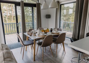 A dining area with a table set for four, surrounded by chairs. - Linwater Caravan Park (Newbridge)