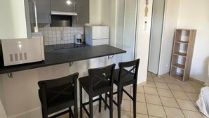 A compact kitchen with a black countertop, a coffee maker, and two black chairs. - Air-conditioned T3 Villa for 6 with pool and parking in Cap d'Agde (Cap d'Agde)