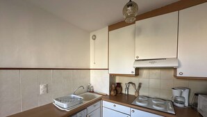 A compact kitchen with white cabinets, a dishwasher, a sink, and a coffee maker. - Studio near beach with terrace in L'Ile-Rousse (L'Île-Rousse)