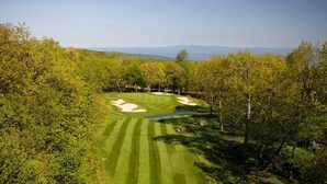 Un parcours de golf doté de bunkers de sable, d’un obstacle d’eau et offrant une vue dégagée sur les montagnes lointaines.
