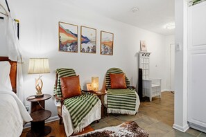 A room with two chairs covered in green and white striped blankets, a small table with a lamp, and three framed landscape paintings on the wall. - Timbers Studio 34 with Wintergreen Advantage (Wintergreen)