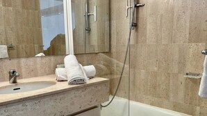 Un baño con lavabo, espejo y ducha.