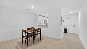 Una cocina moderna con armarios blancos, un microondas y una pequeña encimera.
