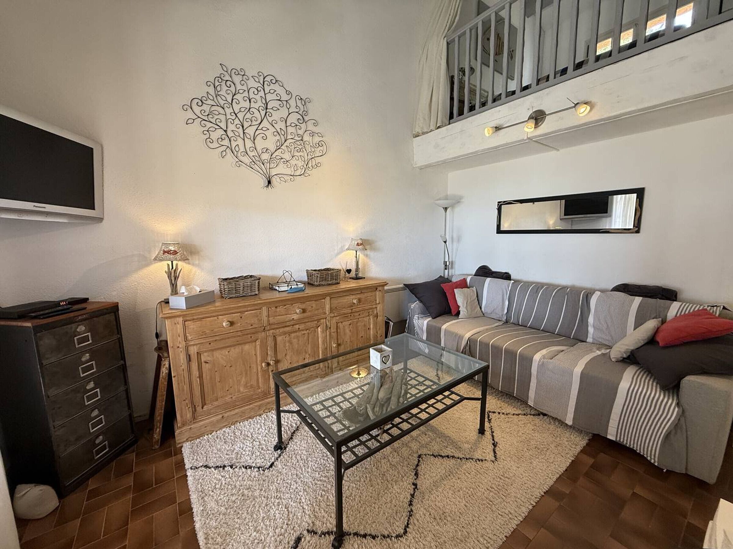 Una sala de estar con sofá, una mesa de centro, televisor y un adorno en la pared.