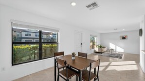 A modern apartment with a dining area, a living room, and a view of the neighborhood. - Sunny Escape | Fresh, Modern Townhome Near Beaches (Port Charlotte)