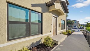 A modern building with large windows, a concrete pathway, and a small garden area. - Sunny Escape | Fresh, Modern Townhome Near Beaches (Port Charlotte)