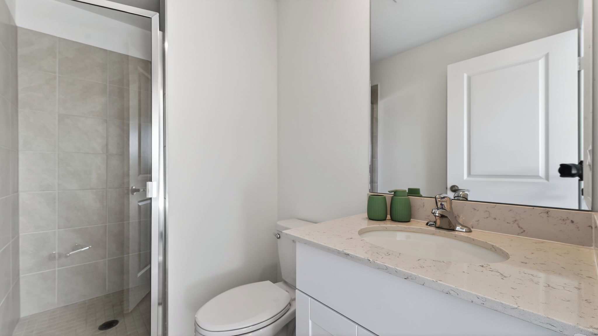 A modern bathroom with a glass shower enclosure, a white toilet, and a marble sink with a mirror above it.