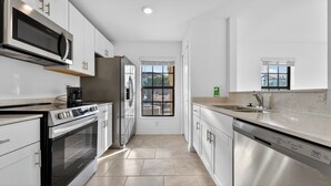 A modern kitchen with stainless steel appliances, white cabinetry, and a window providing a view of the outdoors. - Sunny Escape | Fresh, Modern Townhome Near Beaches (Port Charlotte)