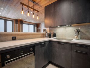 A modern kitchen with dark cabinetry, a stainless steel dishwasher, and a built-in oven. - Renovated ski-in ski-out apartment for 7 people (Courchevel 1850)