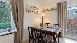 A dining area with a table, chairs, a lamp, and a window with curtains. - Apartment 'Yvette's 2' with Shared Garden and Wi-Fi (Lugau/Erzgeb.)