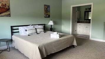 A neatly made bed with a white comforter and pillows, a bedside lamp, and a poster on the wall.