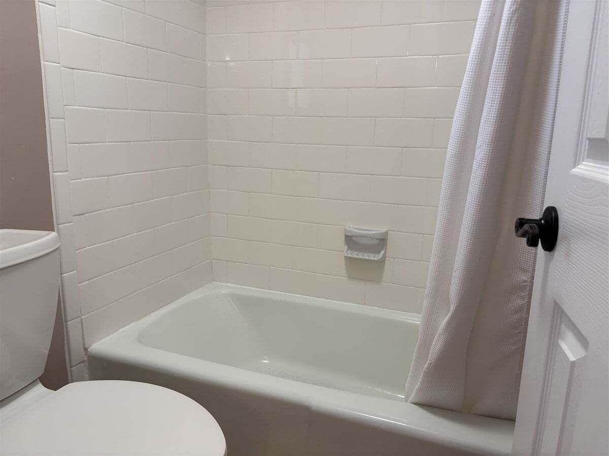 Une salle de bain avec des toilettes blanches, une baignoire et un rideau de douche.