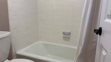 Un bagno con un WC bianco, una vasca e una tenda da doccia.