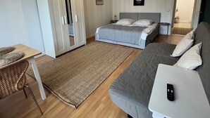 Ein Schlafzimmer mit Bett, Sofa, Schreibtisch und Kleiderschrank.
