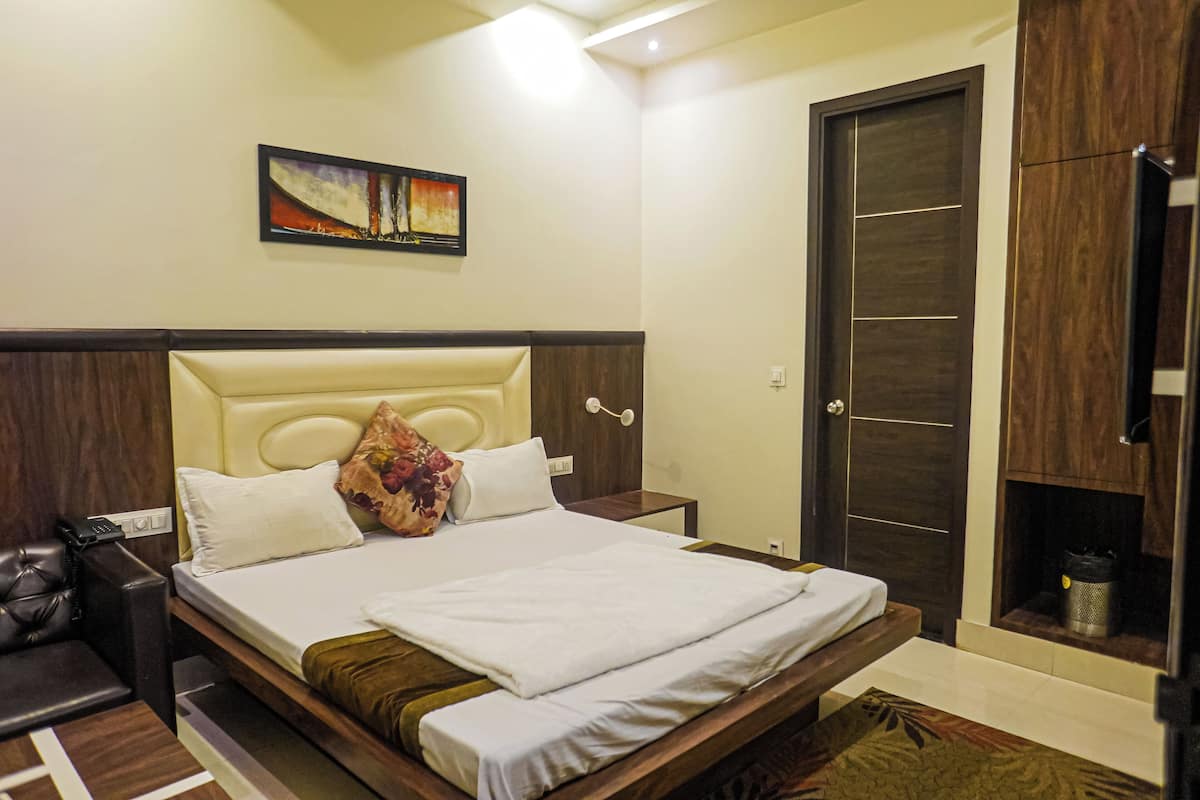 A neatly made bed with a headboard, a bedside table with a lamp, and a painting on the wall.
