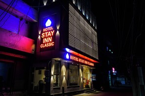 Ein Hotel mit einer auffälligen Neonreklame mit der Aufschrift "HOTEL STAY INN CLASSIC" und einer gemusterten Fassade.