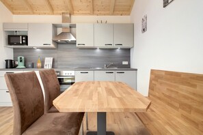Eine moderne Küche mit Holztisch und Stühlen, einer Mikrowelle und einem Herd.
