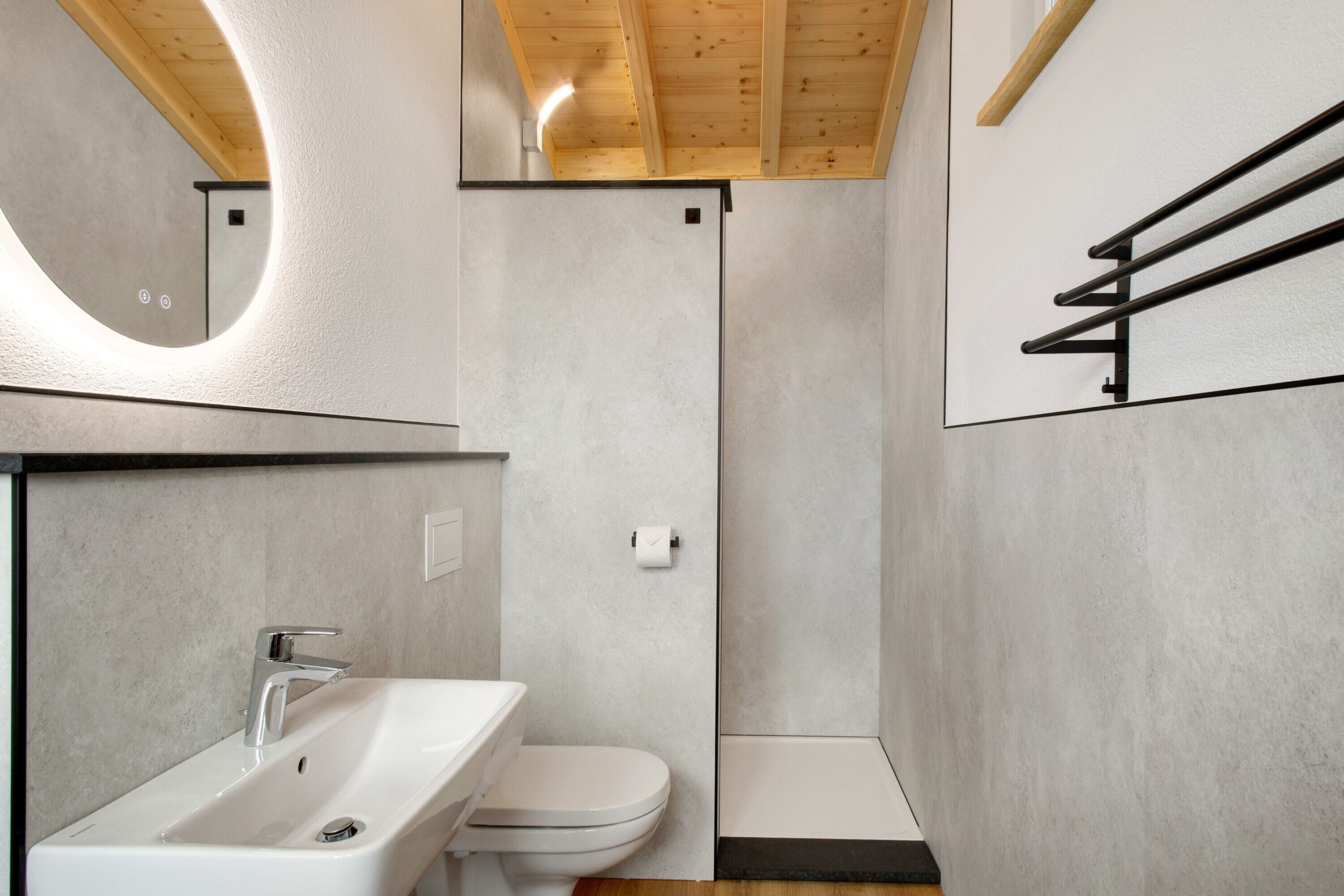 Une salle de bain moderne équipée d’un lavabo, de toilettes et d’une douche.