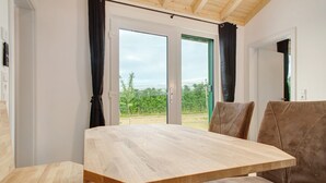 Una habitación con una mesa de madera, sillas tapizadas en tono café y vistas a través de un ventanal.
