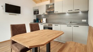 Une cuisine moderne avec une table à manger en bois, deux chaises et des appareils électroménagers intégrés.