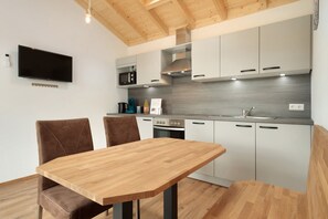 Une cuisine moderne avec une table à manger en bois, deux chaises et des appareils électroménagers intégrés.