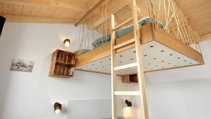 Un lit superposé avec une échelle, des poutres en bois et des étagères fixées au mur.