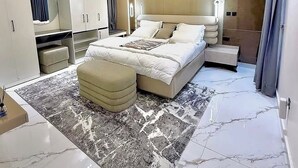 A modern bedroom with a large bed, a bedside table, a wardrobe, and a mirror. - De-Oma Villa Hotel And Apartment (Benin City)