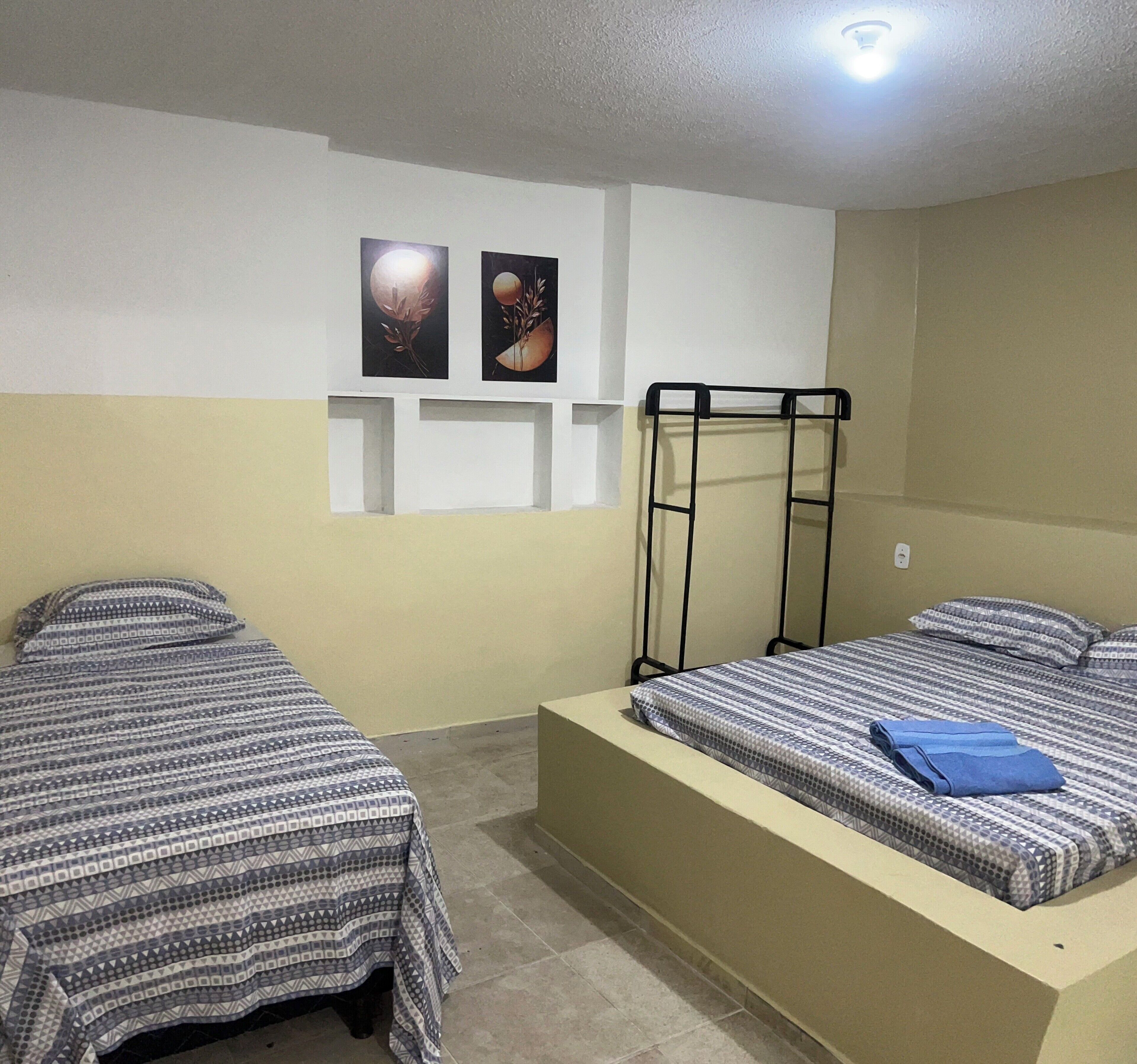 Una habitación con dos camas, una litera y dos cuadros colgados en la pared.