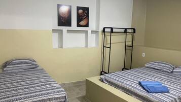 Una habitación con dos camas, una litera y dos cuadros colgados en la pared.