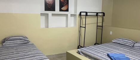 Una habitación con dos camas, una litera y dos cuadros colgados en la pared.