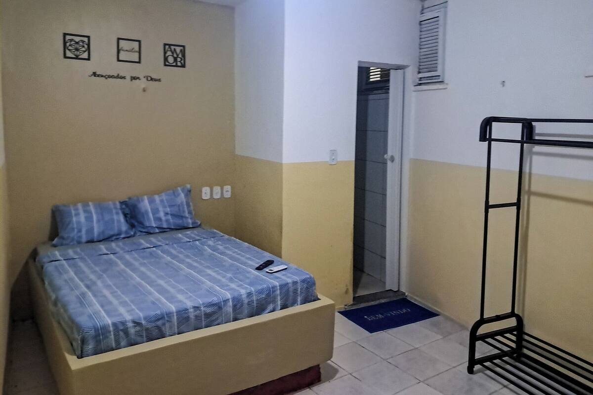 A small, simple room with a bed, a bunk bed, and a door leading to a bathroom.