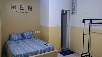 A small, simple room with a bed, a bunk bed, and a door leading to a bathroom.