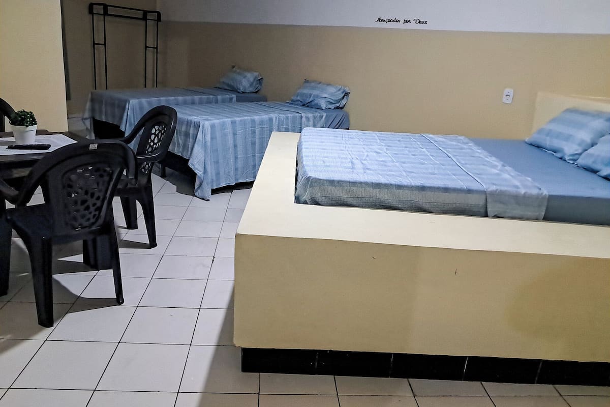 A room with two beds, a table, and a chair.