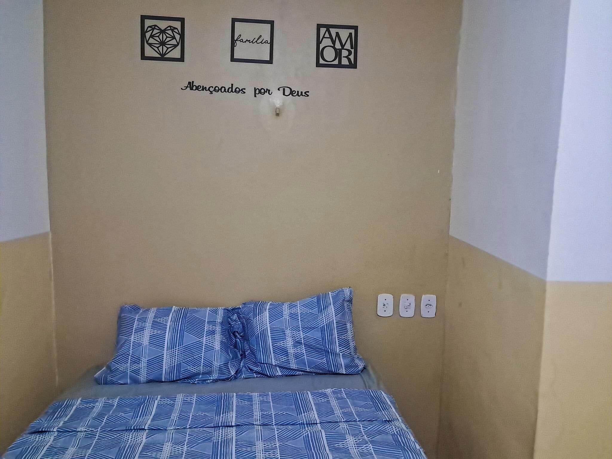 Ein Schlafzimmer mit einem Bett, einer Wand mit drei gerahmten Bildern und einem Lichtschalter.