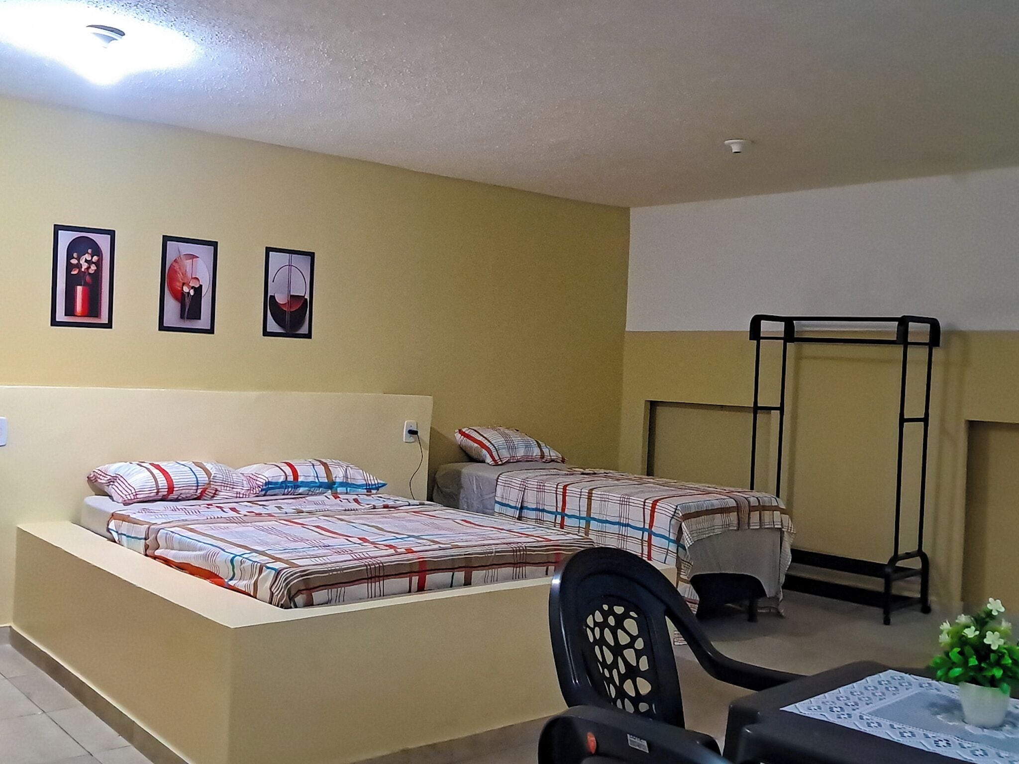 Un dormitorio con dos camas, un escritorio y una silla. Hay tres cuadros enmarcados en la pared.