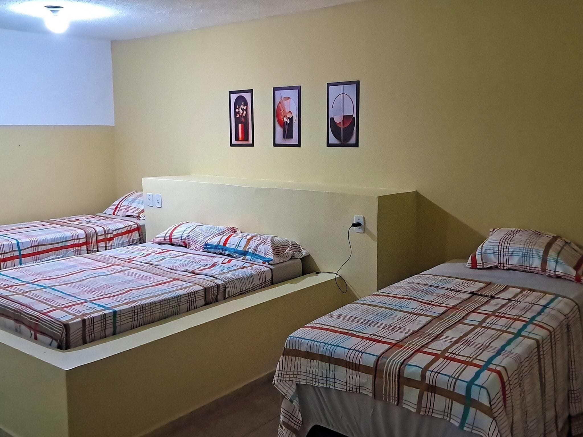 Una habitación de hotel con dos camas individuales, un escritorio pequeño y tres cuadros en la pared.