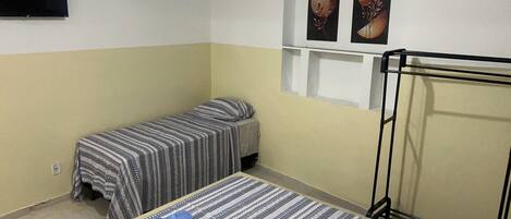 Une chambre avec deux lits, une télévision et des œuvres d’art accrochées au mur.