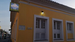 A yellow building with white window frames and shutters, a sign indicating it is a hotel, and a number '356' on the wall. - POUSADA SOLAR DOS LUSITANOS (São Luís)