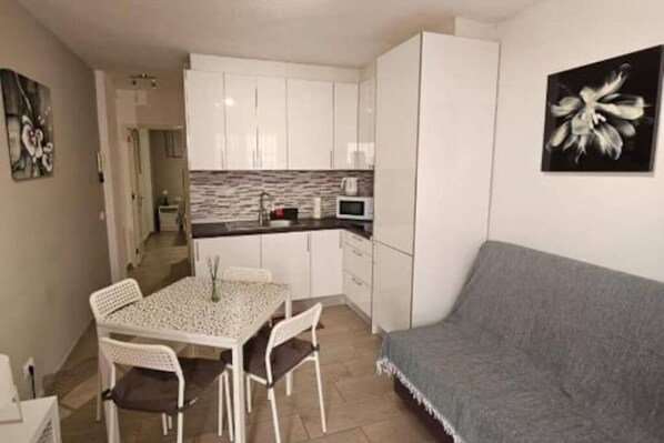 Un espace de vie compact comprenant une kitchenette, un coin repas et un canapé.