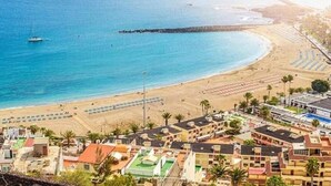 Un pueblo costero con playa, edificios y muelle.