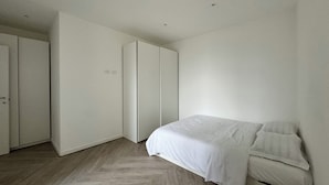 A minimalist bedroom with a bed, a wardrobe, and a closet.