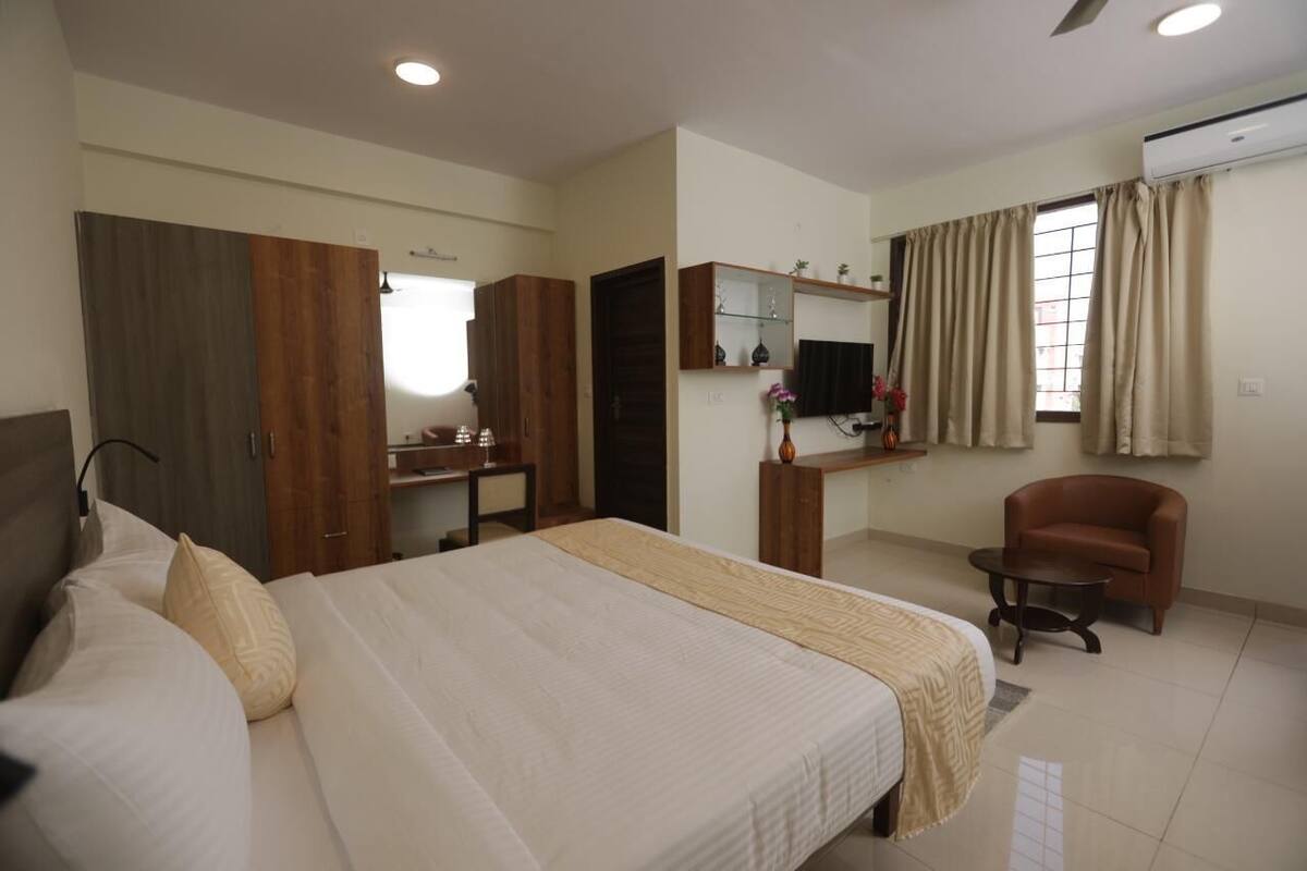 Un dormitorio con cama, escritorio, silla y televisor.