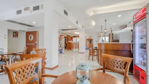 A modern hotel lobby with a dining area, a bar, and a Coca-Cola refrigerator. - Hotiday Peschiera Frassino (Broglie)