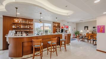A bar area with wooden bar stools, shelves with bottles, and a counter.