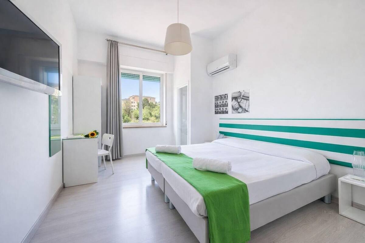 Een moderne hotelkamer met een groot bed, een bureau en een raam met gordijnen.