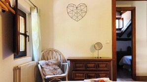 A bedroom with a bed, a chair, a dresser, a mirror, and a geometric wall decoration. - Apartment 3 (Pido)